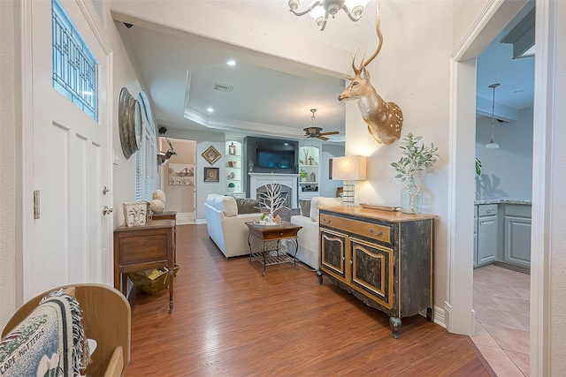 living room featuring dark wood-type flooring, a raised ceiling, and ceiling fan