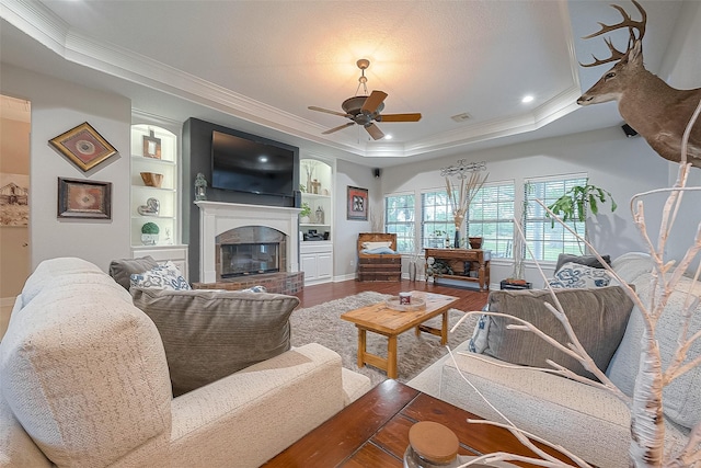 living room with wood-type flooring, a raised ceiling, ceiling fan, and crown molding