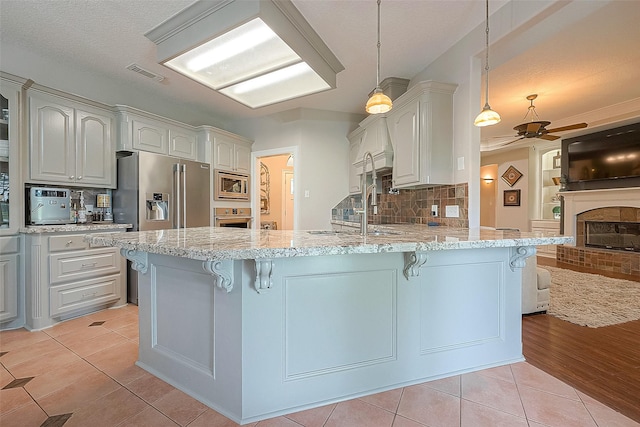 kitchen featuring light stone counters, decorative light fixtures, kitchen peninsula, and appliances with stainless steel finishes