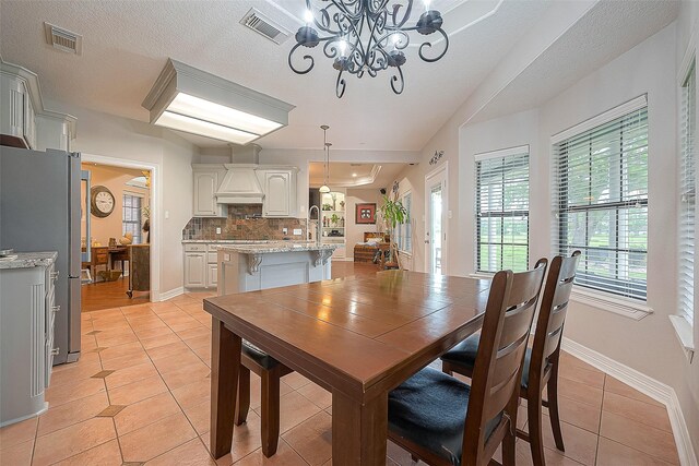 dining area with a notable chandelier, a textured ceiling, and light tile patterned floors