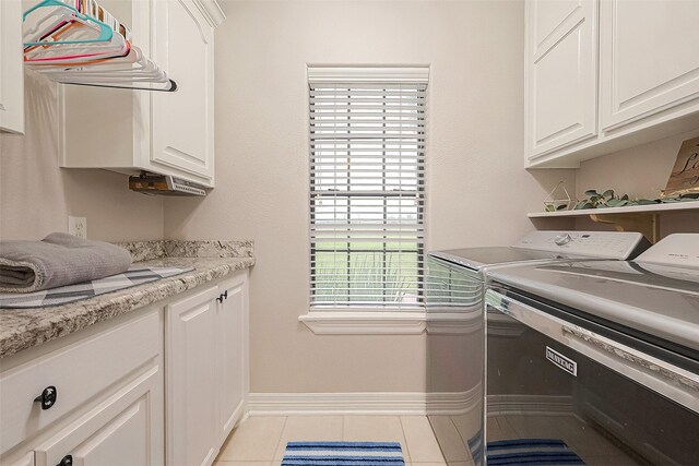 laundry room with light tile patterned floors, washer and clothes dryer, and cabinets