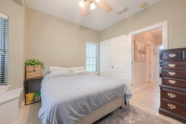 bedroom featuring a textured ceiling, ceiling fan, and light tile patterned flooring