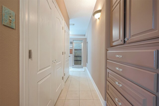 hallway featuring a textured ceiling and light tile patterned floors