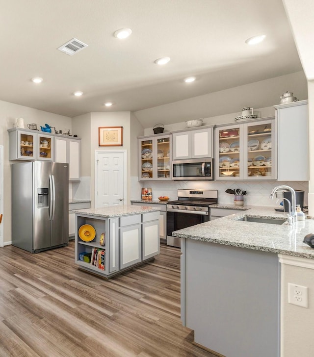 kitchen featuring light stone counters, sink, a kitchen island, and stainless steel appliances