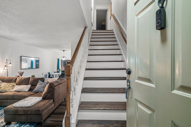 staircase with wood-type flooring and a textured ceiling