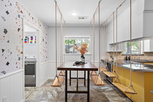 kitchen with backsplash, sink, white cabinets, and washer / dryer