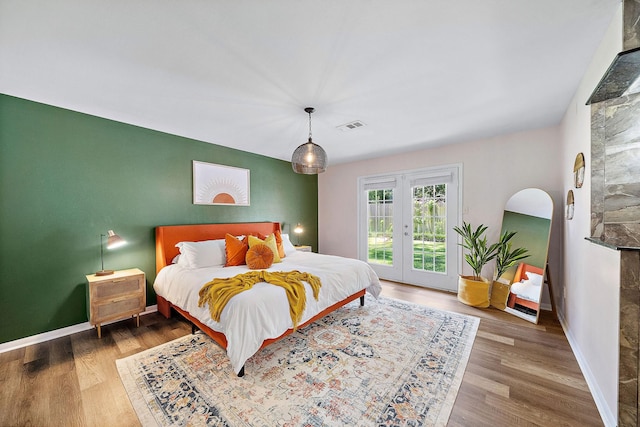 bedroom with access to outside, french doors, and wood-type flooring