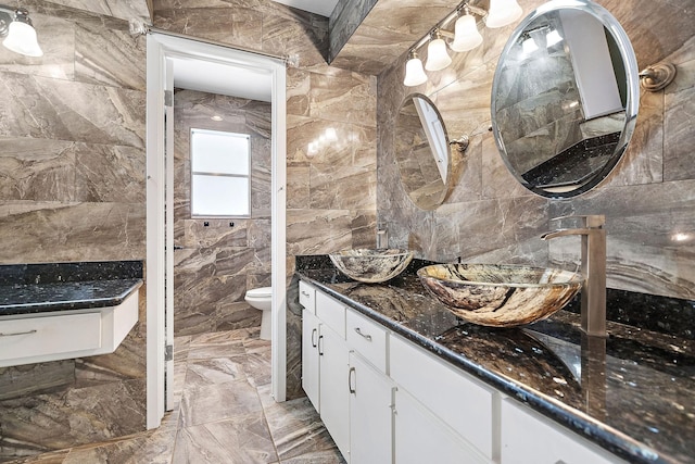 bathroom featuring vanity, toilet, and tile walls