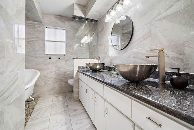 bathroom with vanity, toilet, tile walls, and a tub