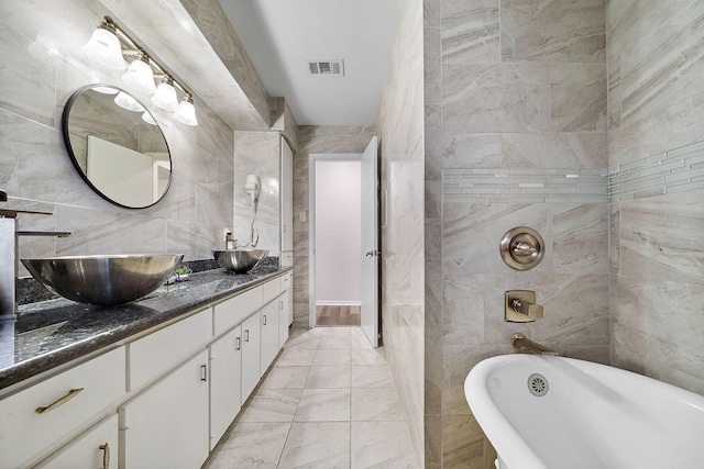 bathroom with a bathing tub, vanity, and tile walls