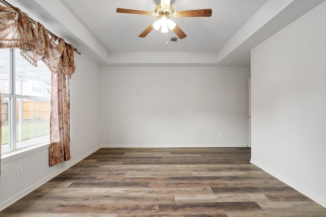 spare room featuring a raised ceiling, ceiling fan, and dark hardwood / wood-style flooring