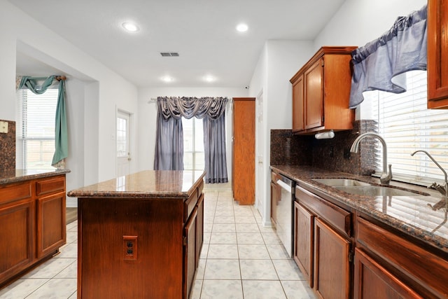 kitchen with dishwasher, a center island, dark stone countertops, and sink