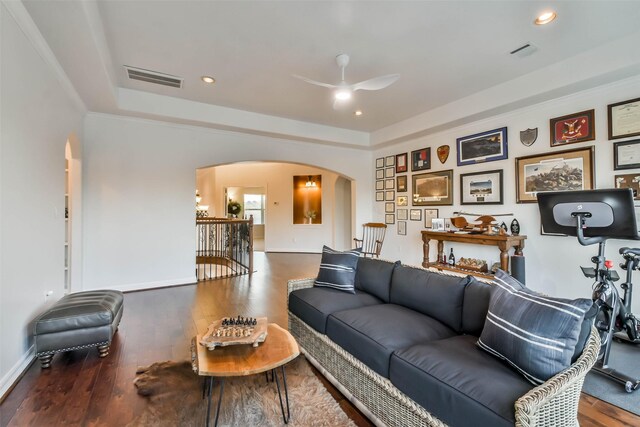 living room with hardwood / wood-style floors, a tray ceiling, and ceiling fan