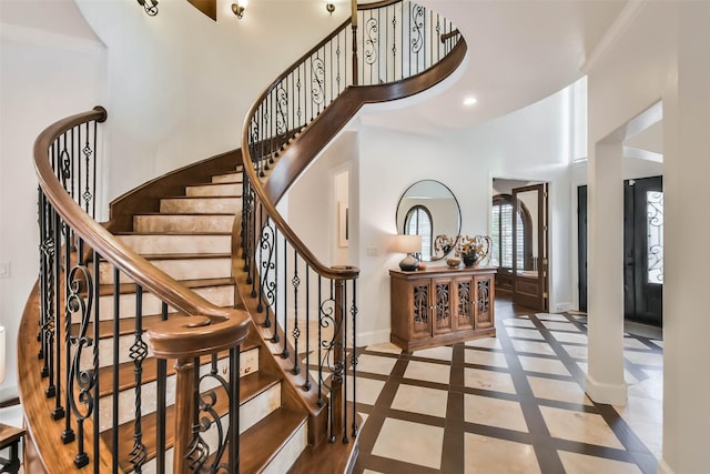 stairs featuring a towering ceiling and ornamental molding