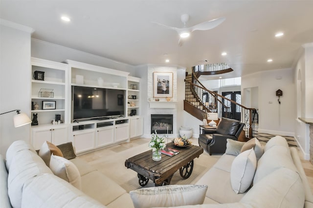 carpeted living room featuring a fireplace, ceiling fan, and crown molding