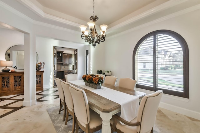 dining room featuring a raised ceiling, ornamental molding, a healthy amount of sunlight, and a notable chandelier