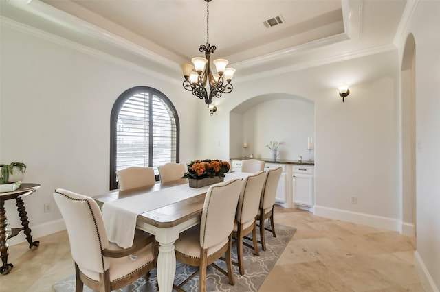 dining space featuring a chandelier, ornamental molding, and a tray ceiling