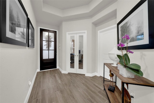 entrance foyer featuring french doors, light wood-type flooring, and a raised ceiling