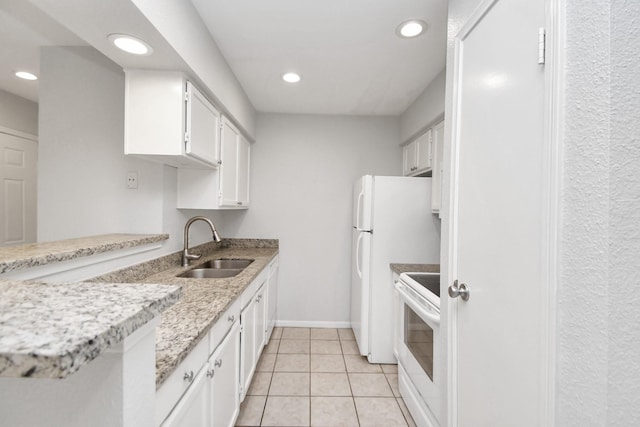 kitchen with light stone countertops, sink, light tile patterned floors, white cabinets, and range