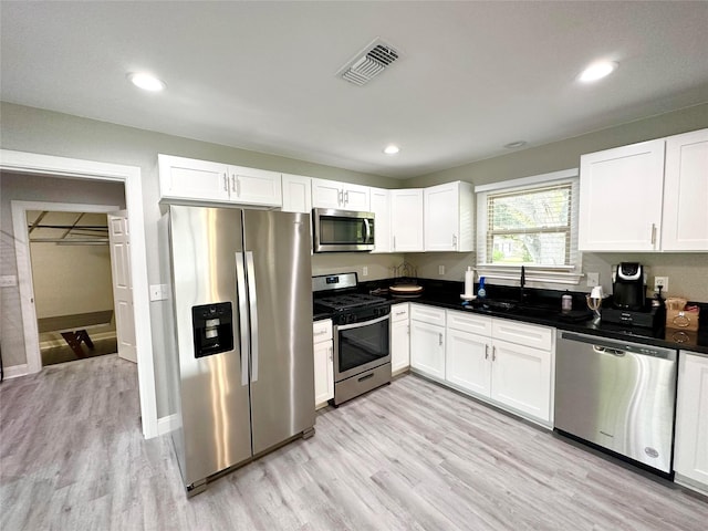 kitchen with white cabinets, stainless steel appliances, and light hardwood / wood-style floors