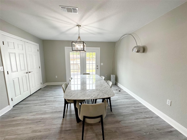 dining room with hardwood / wood-style floors and an inviting chandelier