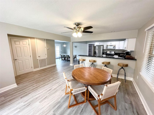 dining space featuring a textured ceiling, light hardwood / wood-style flooring, and ceiling fan