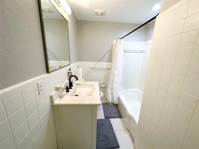 full bathroom featuring tile patterned floors, shower / bath combination with curtain, toilet, vanity, and tile walls