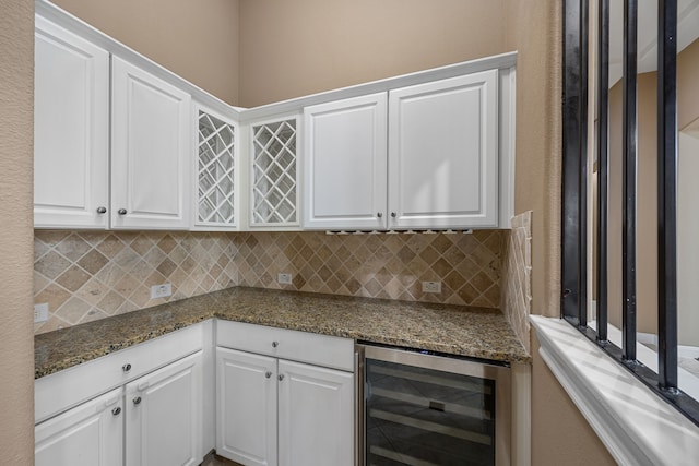 kitchen with decorative backsplash, white cabinetry, beverage cooler, and dark stone counters