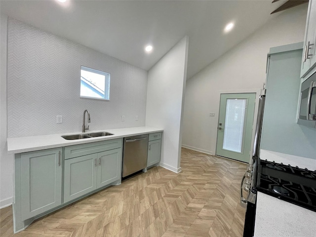 kitchen featuring lofted ceiling, sink, appliances with stainless steel finishes, and light parquet floors