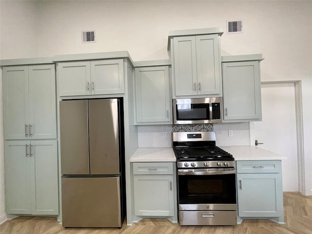 kitchen with light parquet floors, appliances with stainless steel finishes, and tasteful backsplash