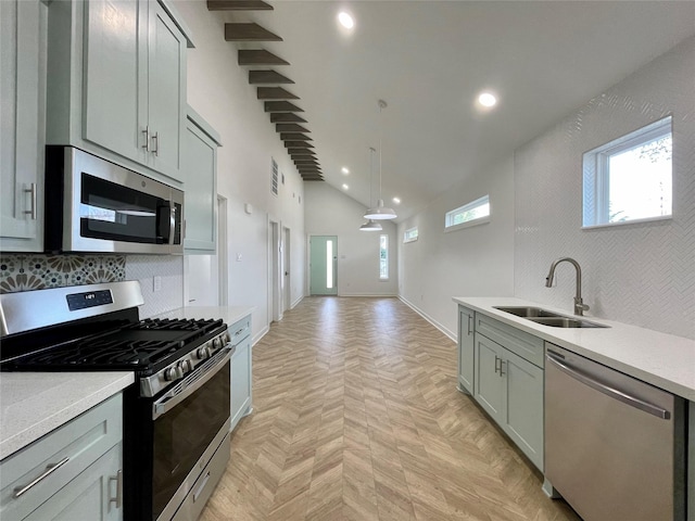 kitchen featuring sink, hanging light fixtures, stainless steel appliances, backsplash, and light parquet flooring