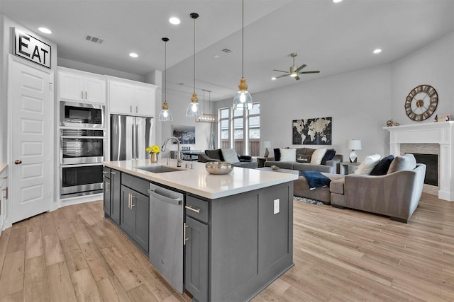 kitchen featuring a kitchen island with sink, white cabinets, sink, gray cabinets, and appliances with stainless steel finishes