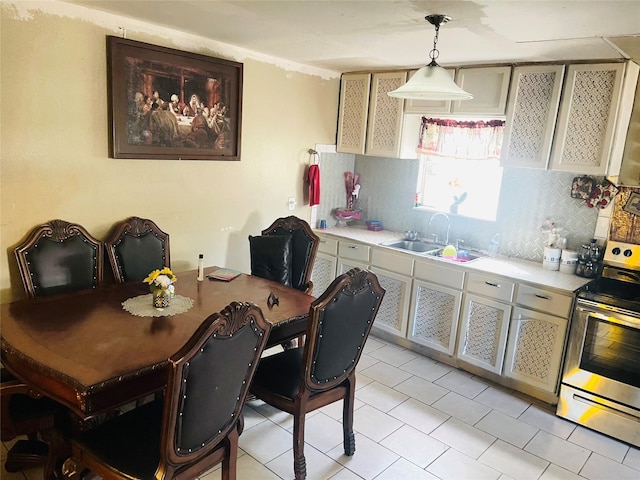 kitchen with tasteful backsplash, electric stove, sink, and decorative light fixtures