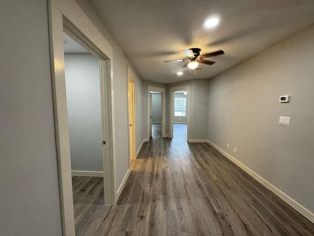 hallway with a textured ceiling and dark wood-type flooring