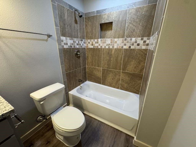 full bathroom with vanity, wood-type flooring, tiled shower / bath combo, and toilet