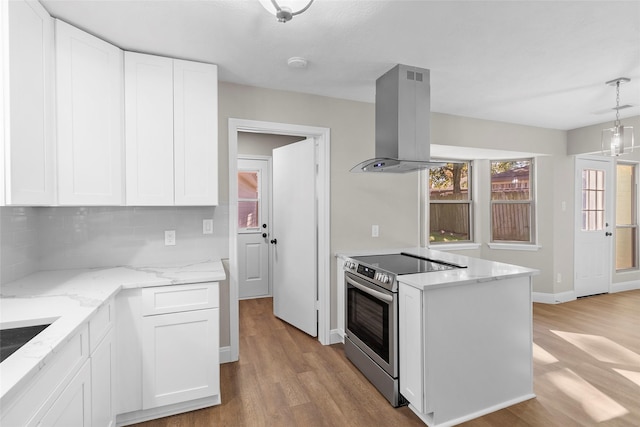 kitchen with stainless steel range with electric stovetop, backsplash, white cabinets, and island exhaust hood