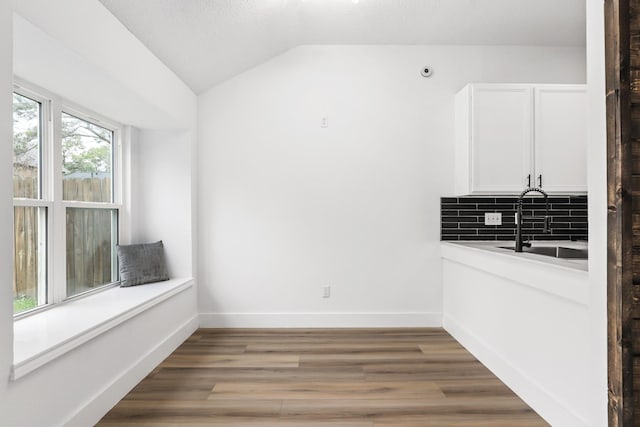 unfurnished dining area with wood-type flooring, a textured ceiling, lofted ceiling, and sink