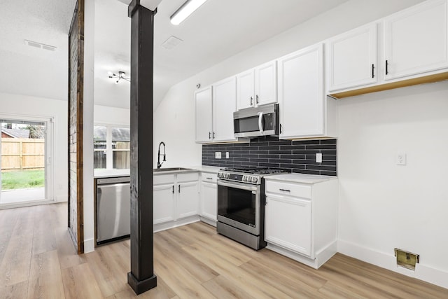 kitchen featuring white cabinetry, sink, stainless steel appliances, tasteful backsplash, and light wood-type flooring