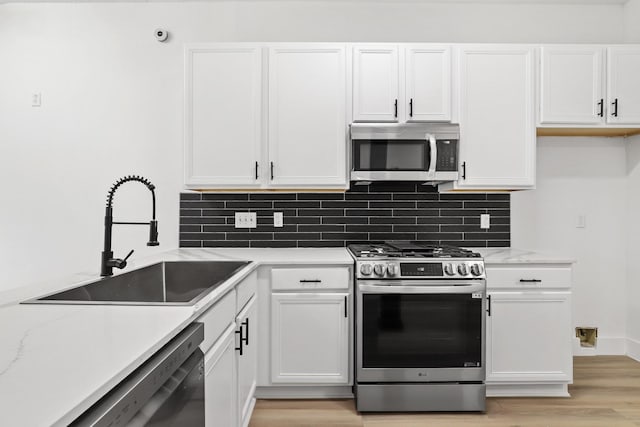 kitchen with white cabinets, backsplash, sink, and stainless steel appliances