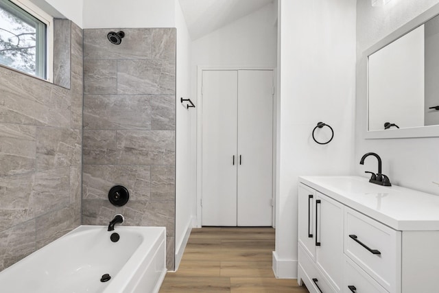 bathroom featuring hardwood / wood-style flooring, tiled shower / bath combo, lofted ceiling, and vanity