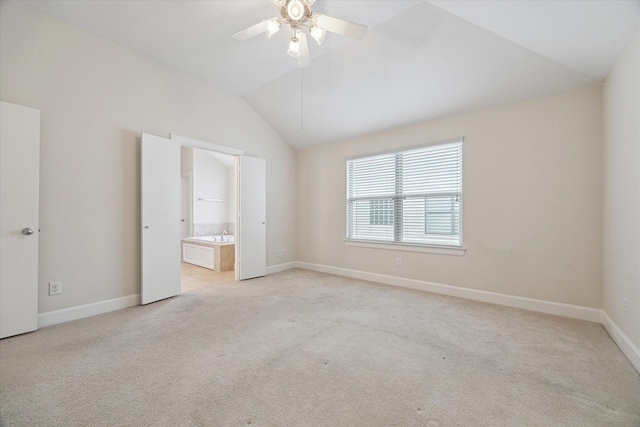 unfurnished bedroom featuring vaulted ceiling, light carpet, connected bathroom, and ceiling fan