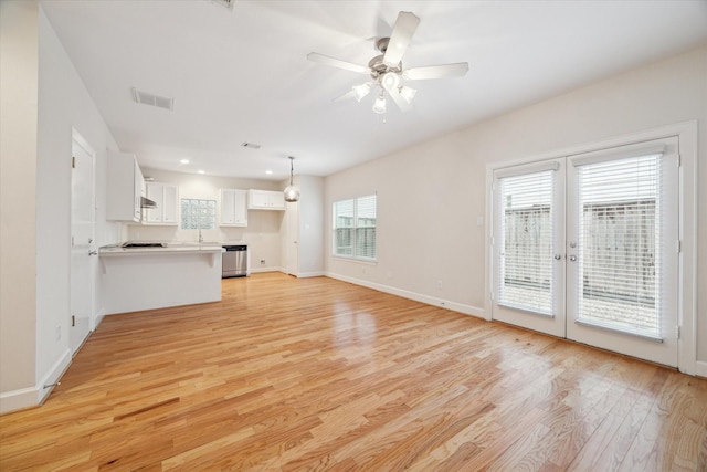 unfurnished living room with french doors, light wood-type flooring, and ceiling fan