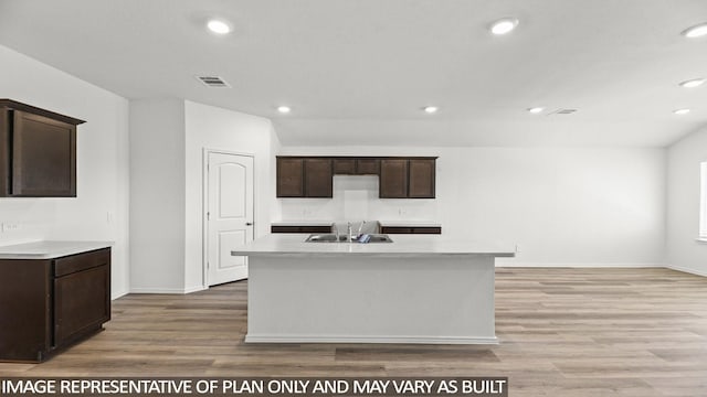 kitchen with a kitchen island with sink, sink, and light wood-type flooring