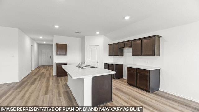 kitchen with light wood-type flooring, sink, dark brown cabinetry, and an island with sink