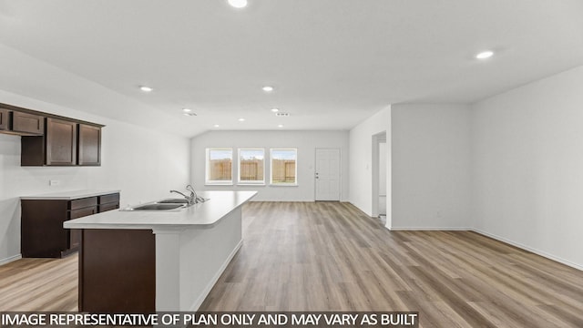 kitchen featuring dark brown cabinetry, light hardwood / wood-style floors, a kitchen island with sink, and sink