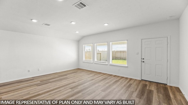 empty room with light hardwood / wood-style floors and lofted ceiling