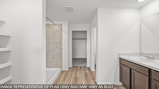 bathroom with a tile shower, hardwood / wood-style floors, and vanity