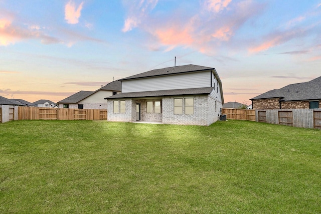 back house at dusk with cooling unit and a lawn