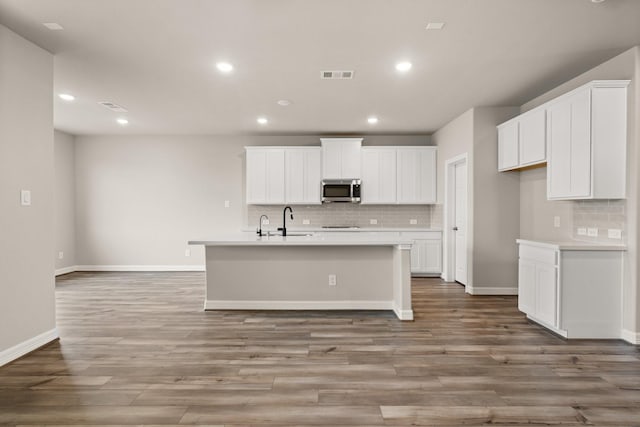 kitchen with a kitchen island with sink, light hardwood / wood-style flooring, white cabinets, and sink