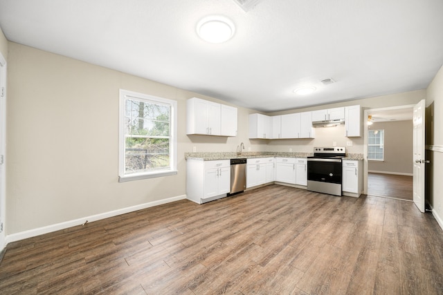 kitchen with white cabinets, light stone counters, wood-type flooring, and stainless steel appliances